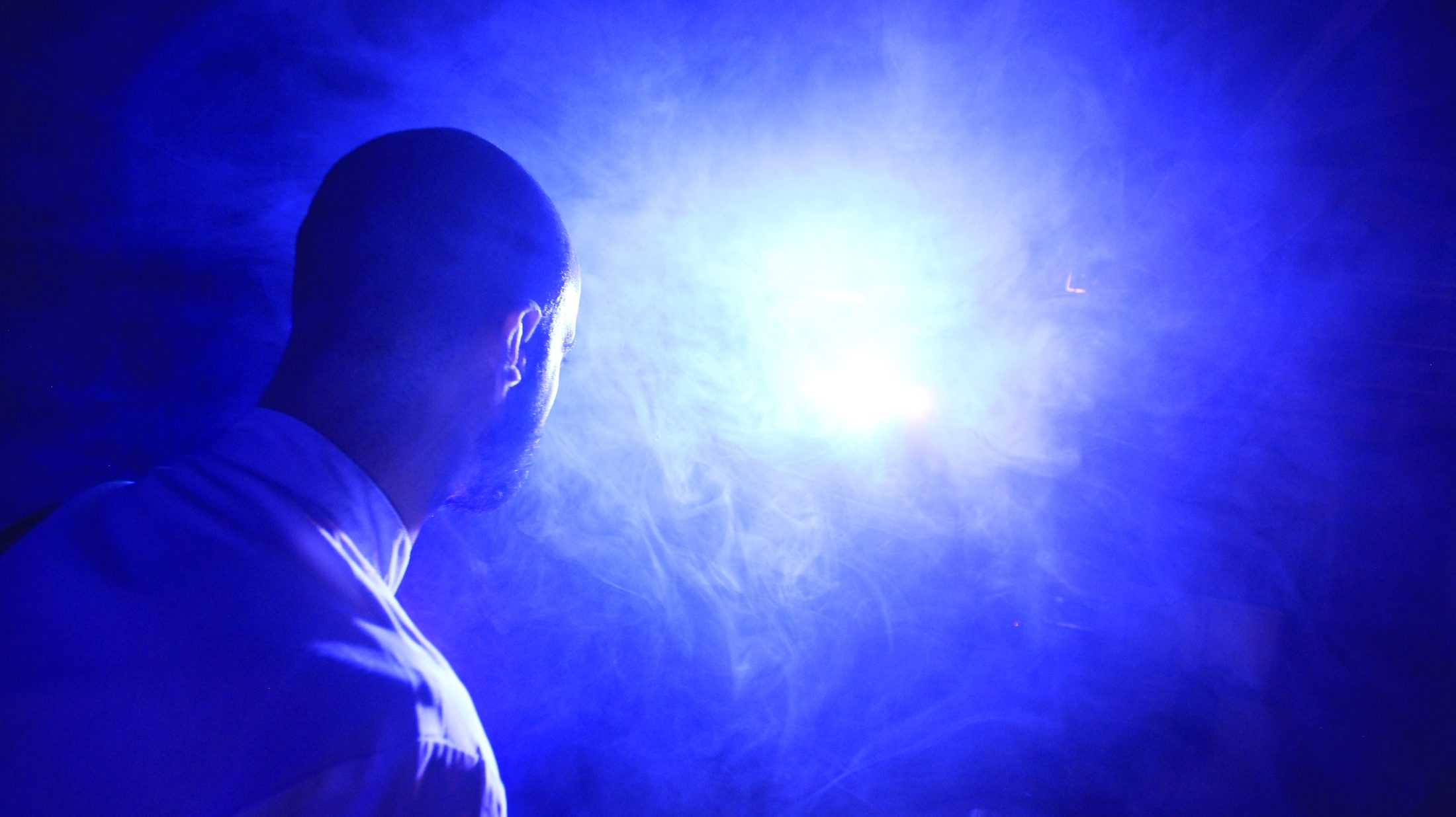 Stefano Kajatt in profile, silhouetted against glowing blue haze
