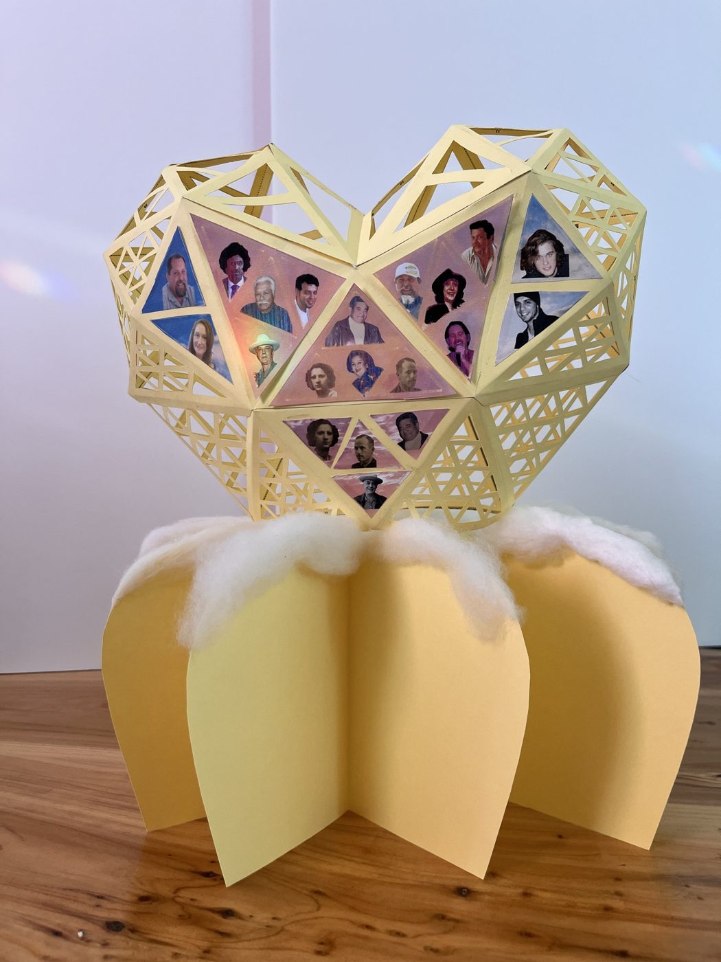The complete paper maquette: portraits held in the lattice heart above a petal pedestal with a polyfill cloud