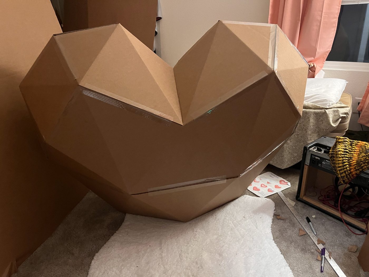 The first full-size cardboard heart taped together on a bedroom floor