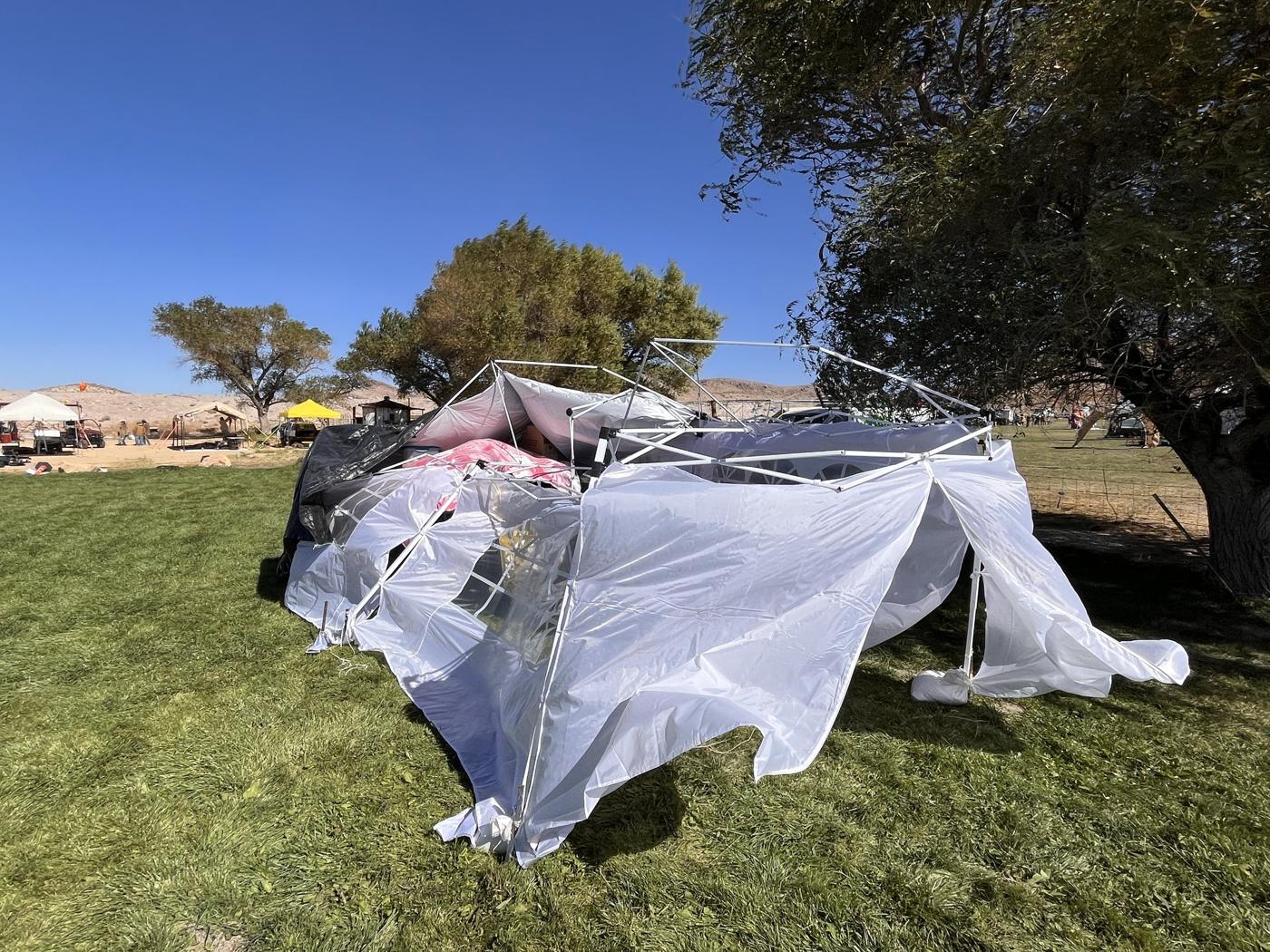 The event tent flattened by desert wind the morning after, the golden heart visible through the wreckage