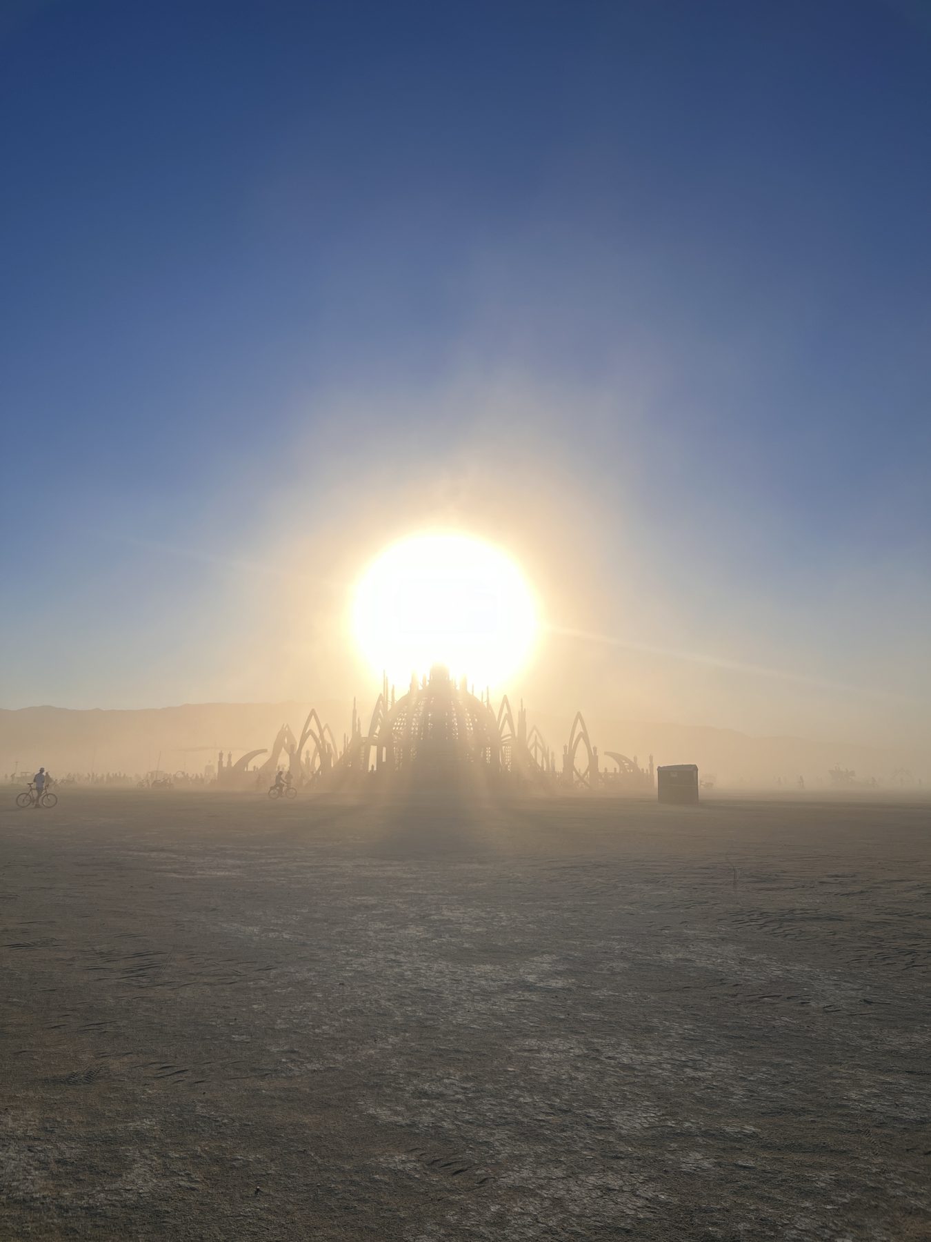 The Temple at Burning Man silhouetted against the rising sun through desert dust